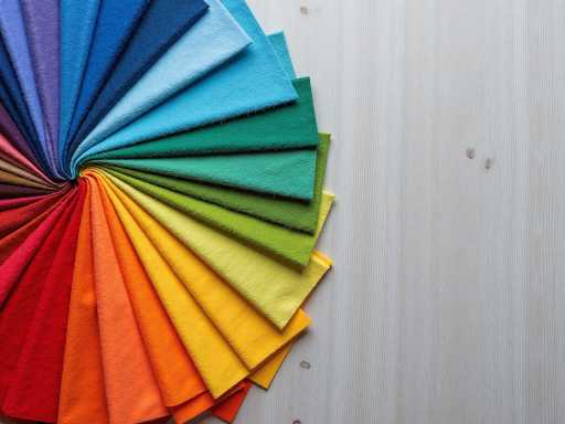 Colorful textile fabrics displayed on wooden surfaces, various fabric textures and patterns, professional product photography, soft natural lighting